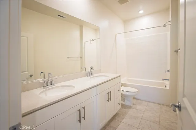 a spacious bathroom with a granite countertop sink a toilet and a mirror