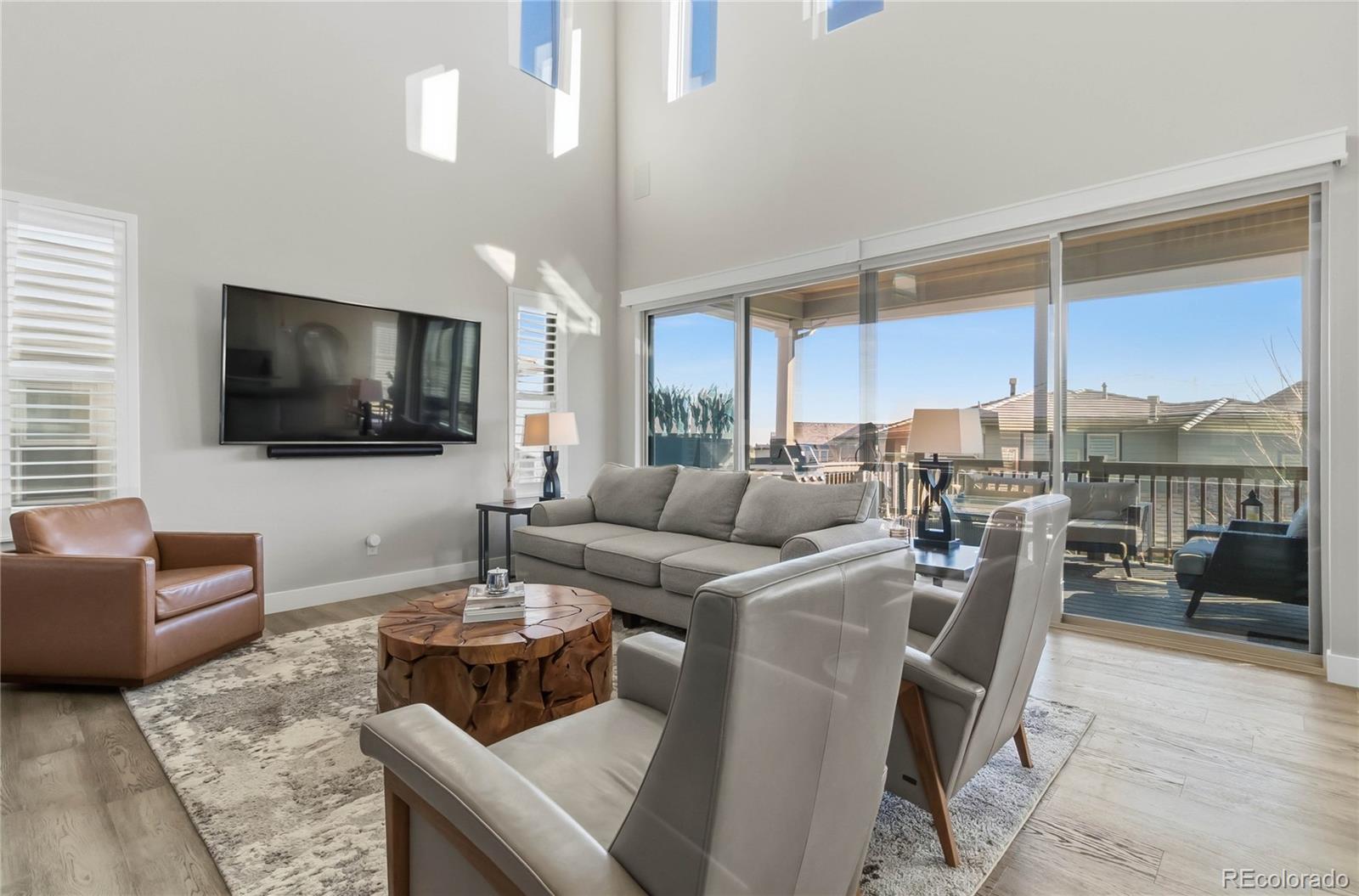 489 Meadowleaf Lane Highlands Ranch, CO 80126 - Photo 10 of 50 a living room with furniture a flat screen tv and a floor to ceiling window
