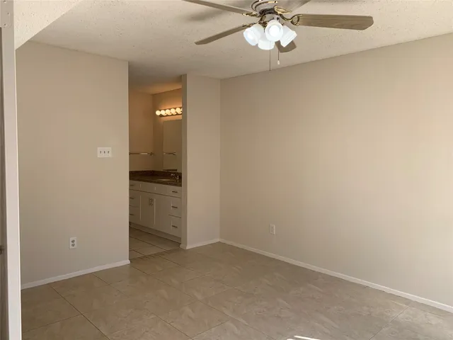 an empty room with windows and fan