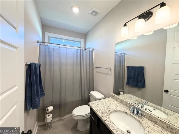 a bathroom with a granite countertop sink toilet and shower