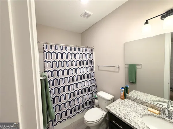 a bathroom with a granite countertop toilet a sink and a mirror