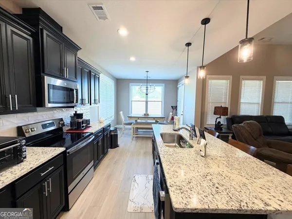 a large kitchen with kitchen island a large counter top space a sink stainless steel appliances and cabinets