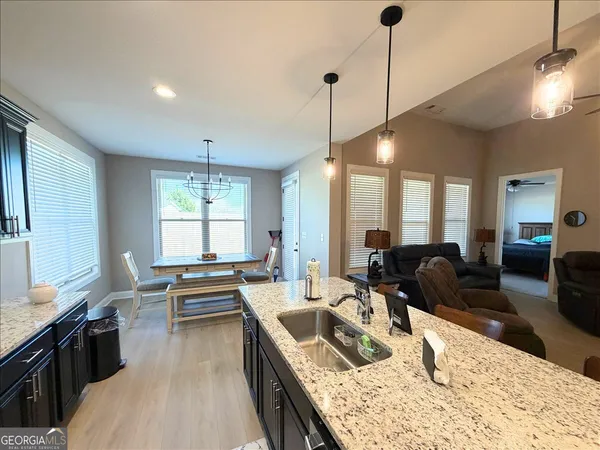 a large kitchen with kitchen island a large counter top space a sink a stove and a window