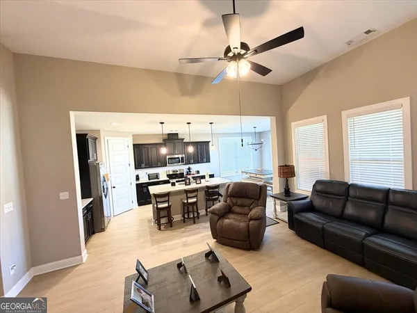 a living room with furniture kitchen view and a window