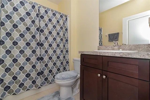 a bathroom with a granite countertop sink toilet and mirror