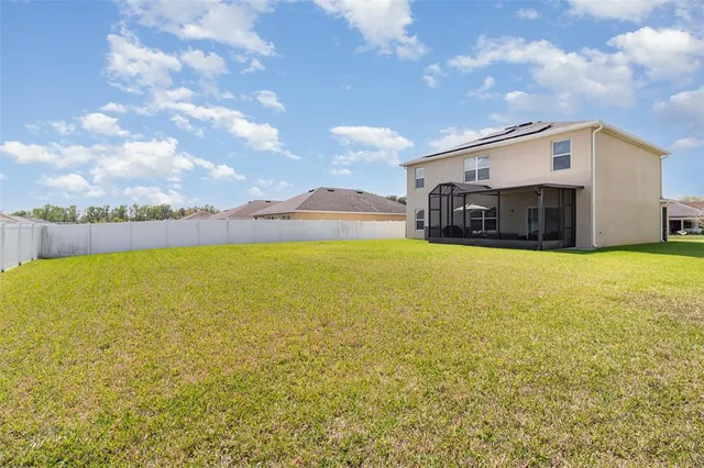 a view of open pool with lawn chairs and large tree