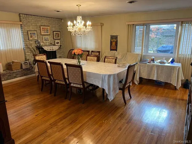 a dining room with wooden floor a chandelier a wooden table and chairs