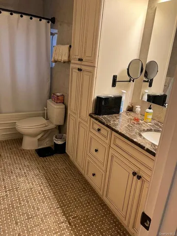 a bathroom with a granite countertop toilet sink and mirror