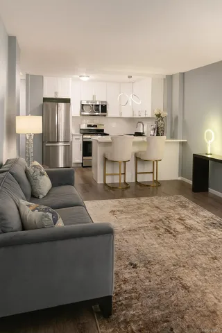 a living room with stainless steel appliances kitchen island granite countertop a couch and a refrigerator