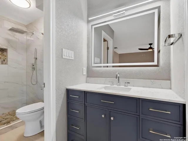 a bathroom with a toilet a sink a vanity and mirror