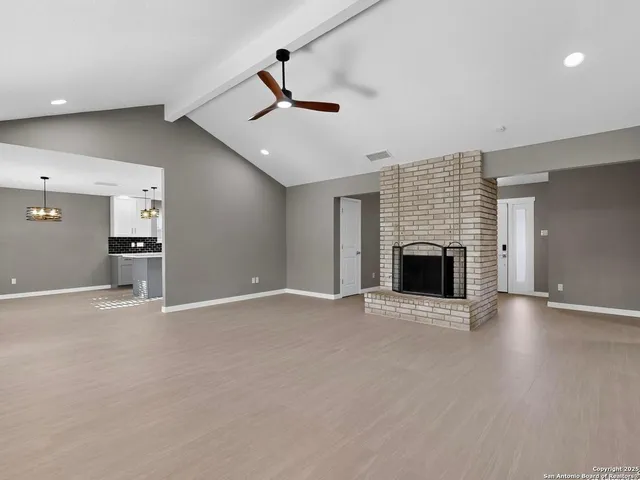 an empty room with windows and fireplace