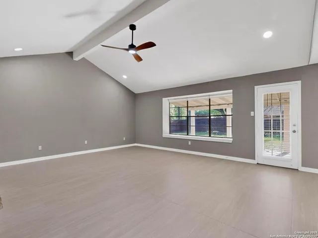 a view of an empty room with a window and wooden floor