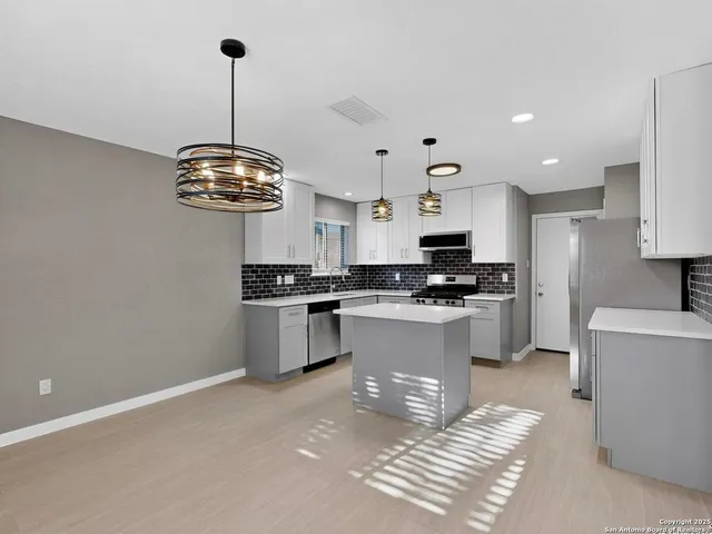 a kitchen with stainless steel appliances kitchen island granite countertop a sink a stove and refrigerator