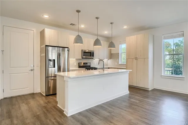 a kitchen with a sink chandelier and wooden floor