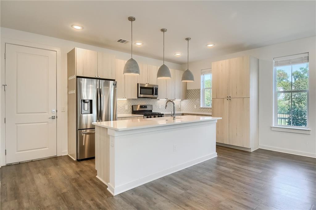2624 Metcalfe Road, Unit 7 Austin, TX 78741 - Photo 8 of 31 a large kitchen with stainless steel appliances kitchen island a large counter top and a wooden floors