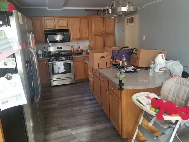 a kitchen with stainless steel appliances a stove a sink dishwasher a refrigerator white cabinets and wooden floor