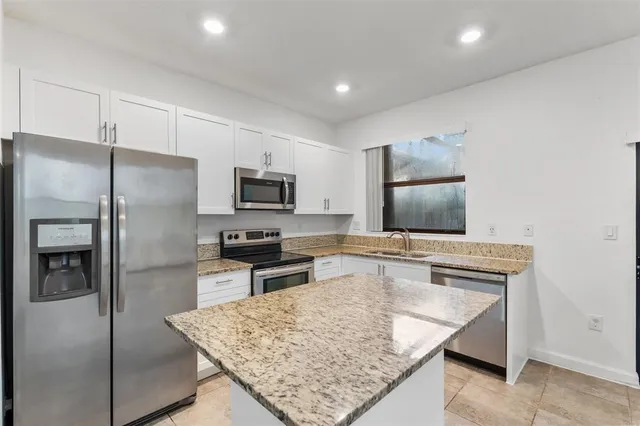 a kitchen with stainless steel appliances granite countertop a refrigerator stove top oven and sink