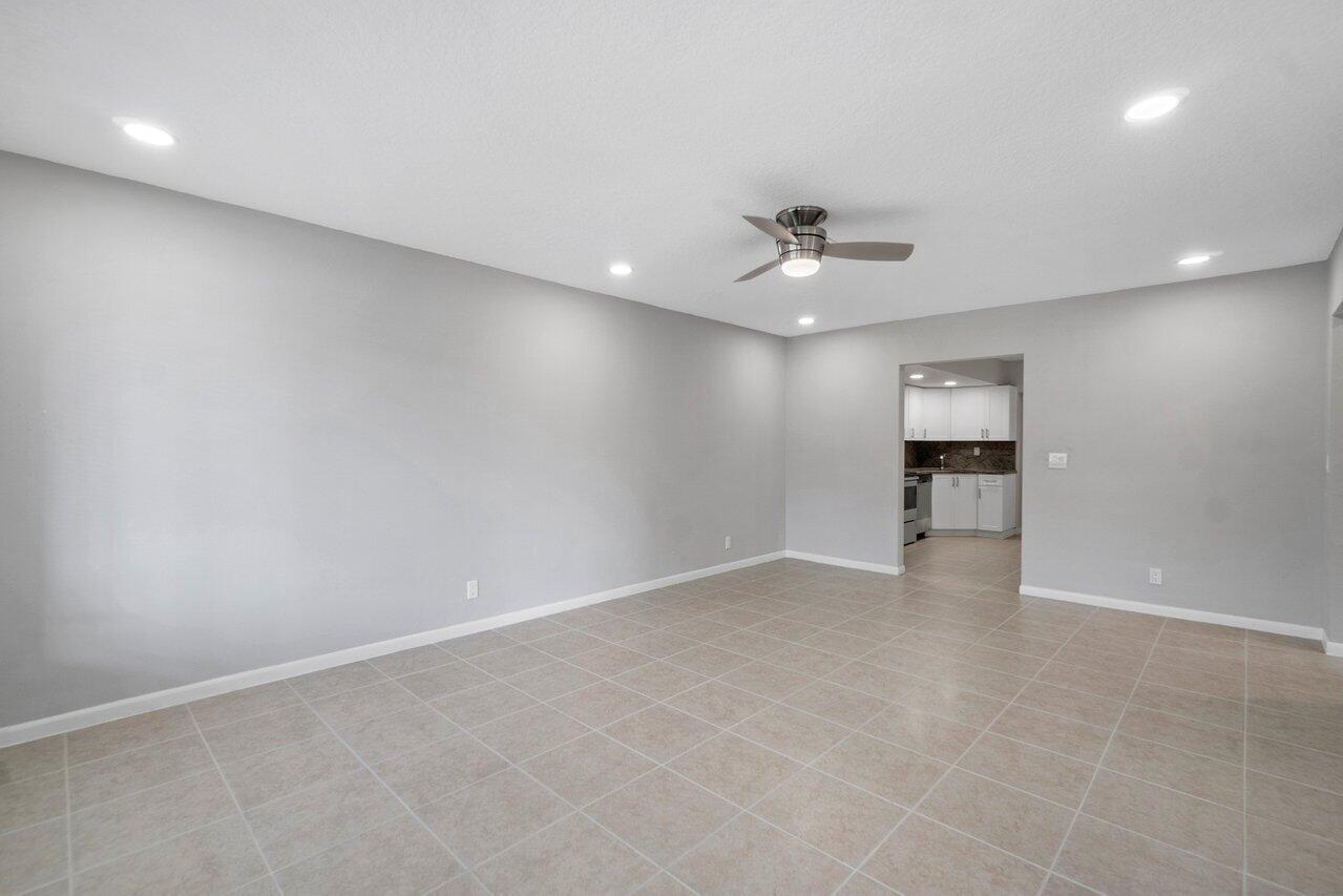 209 Southwest 6th Street, Unit 209 Boca Raton, FL 33432 - Photo 12 of 37 an empty room with a chandelier fan and windows
