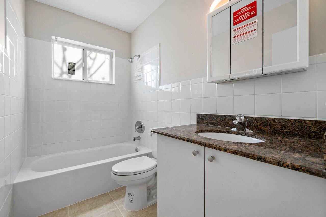 209 Southwest 6th Street, Unit 209 Boca Raton, FL 33432 - Photo 22 of 37 a bathroom with a granite countertop sink a toilet and bathtub