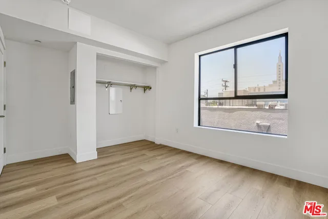 a view of an empty room with wooden floor and a window