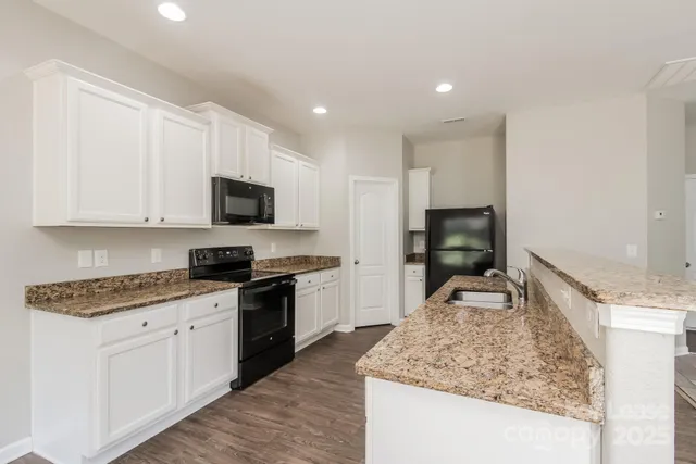 a kitchen with granite countertop white cabinets and stainless steel appliances