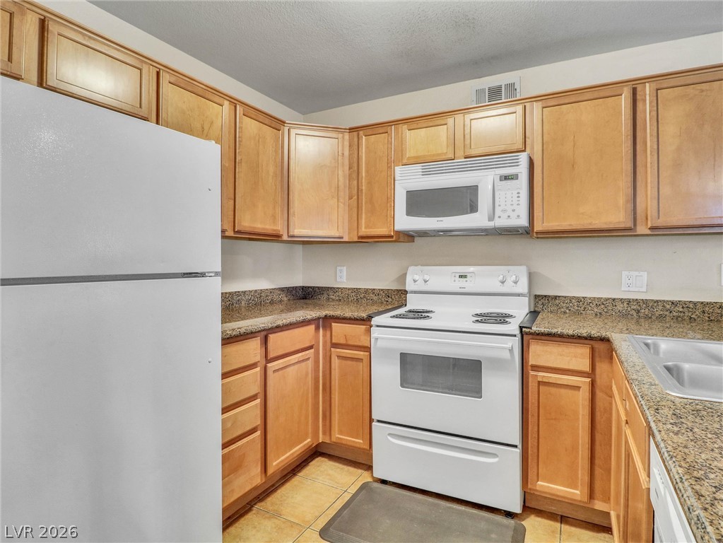 3145 East Flamingo Road, Unit 2129 Las Vegas, NV 89121 - Photo 9 of 43 A well-appointed kitchen showcasing durable granite counters and natural wood cabinetry.