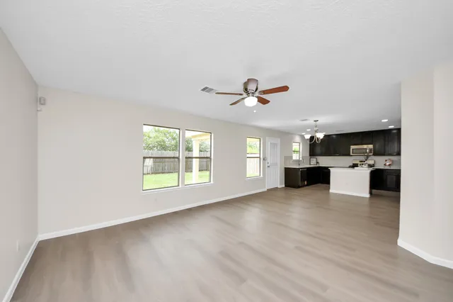 a view of an empty room with a kitchen and a window