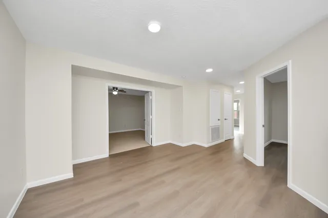 a view of an empty room with wooden floor and closet
