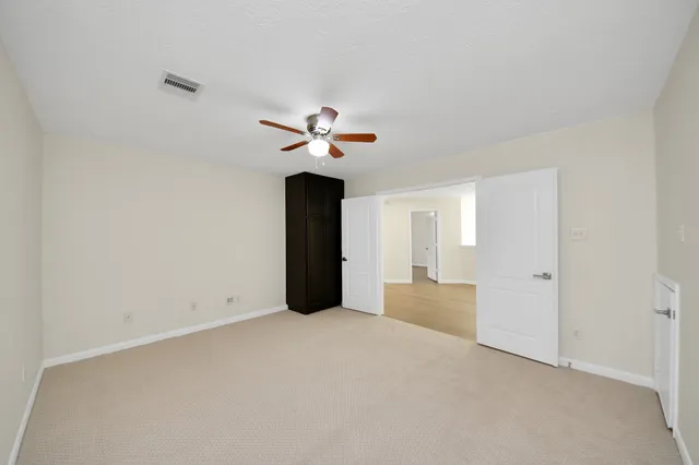 a view of an empty room with a chandelier fan