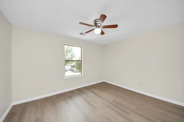 a view of empty room with wooden floor and fan