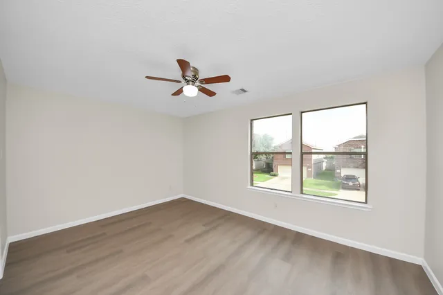 an empty room with wooden floor and windows