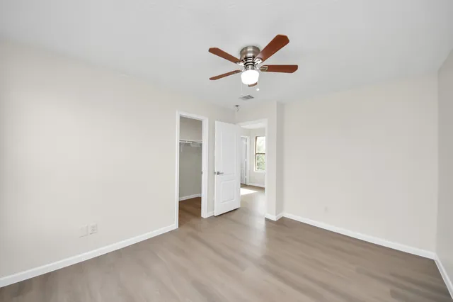 an empty room with wooden floor and windows