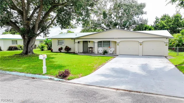 a view of a house with a yard and large tree