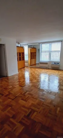 a view of an empty room with window and wooden floor