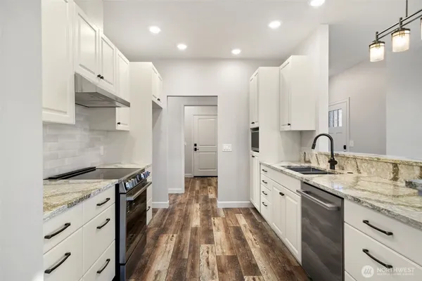 a kitchen with granite countertop a sink stove and cabinets