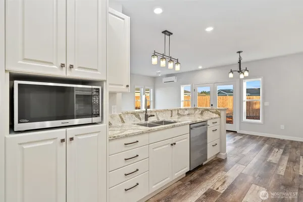 a kitchen with stainless steel appliances kitchen island granite countertop a sink a stove and a microwave