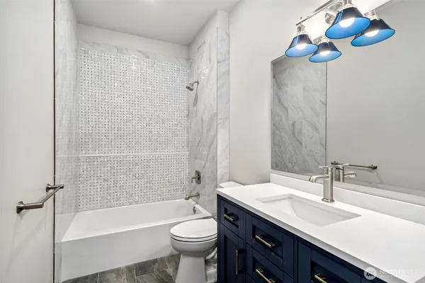 a bathroom with a sink a toilet a mirror a bathtub and shower