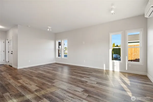 a view of an empty room with window and wooden floor