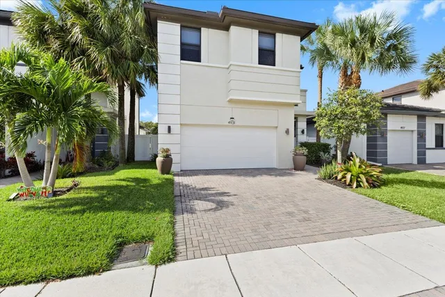a front view of a house with a yard and palm tree