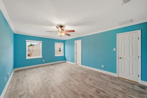 a view of an empty room with window and chandelier fan