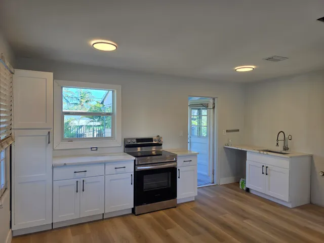 a kitchen with granite countertop a stove a sink wooden floor and cabinets