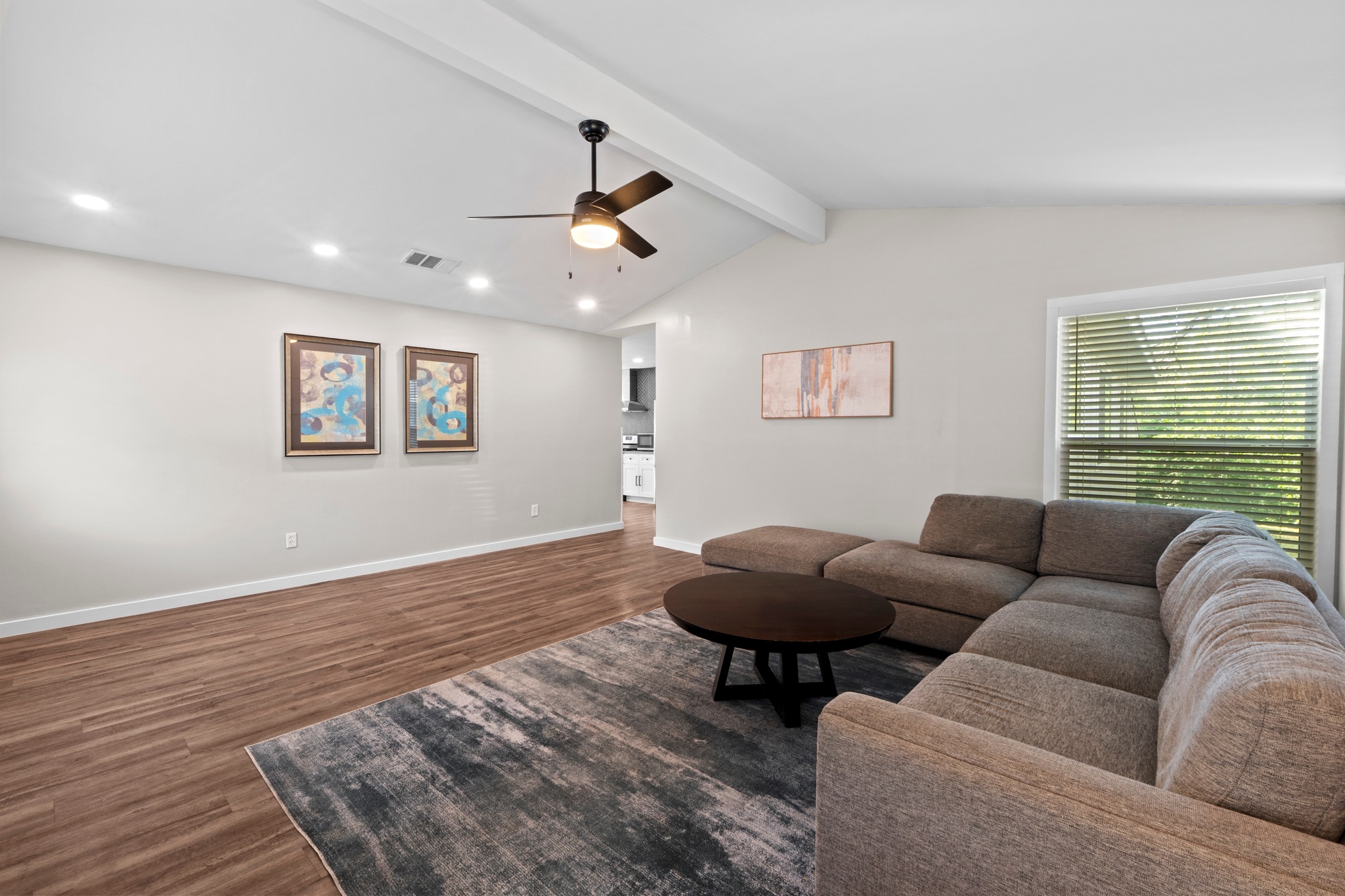 11811 Rotherham Drive Austin, TX 78754 - Photo 5 of 37 Well-lit living room featuring vaulted ceilings, a ceiling fan, and durable wood flooring.