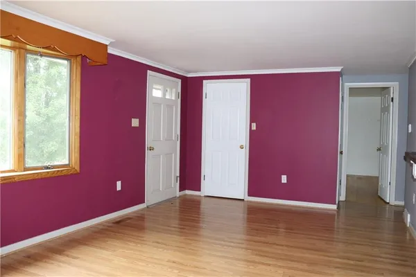 a view of an empty room with window and wooden floor