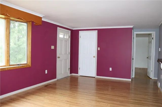 a view of an empty room with window and wooden floor
