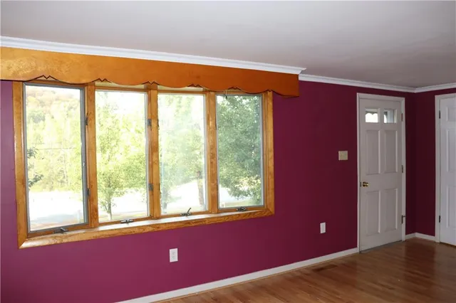 a view of an empty room with wooden floor and windows