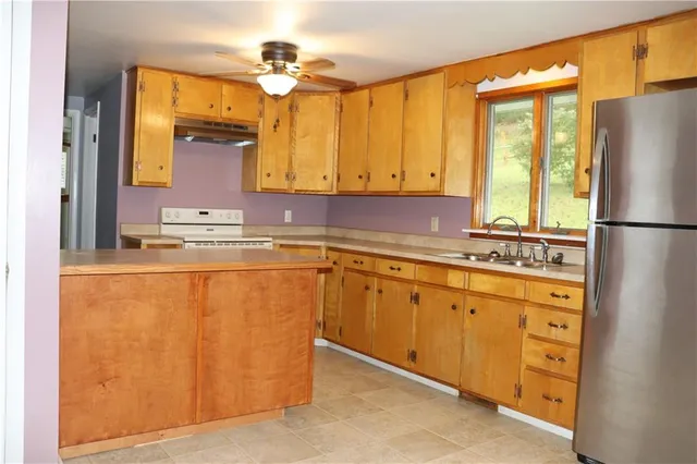 a kitchen with stainless steel appliances granite countertop a refrigerator a sink and white cabinets