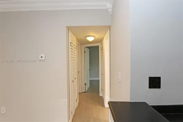 a view of a hallway with wooden floor and a bathroom