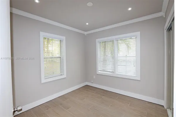 an empty room with wooden floor and windows