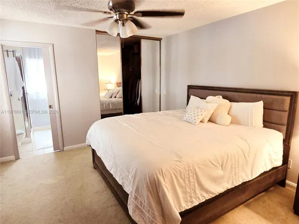 a large bed in a bedroom next to a window and a chandelier