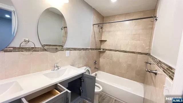 a bathroom with a sink and mirror with bathtub